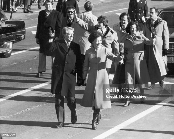 Full-length portrait of President Jimmy Carter holding First Lady Rosalynn Carter's hand, while they walk down a street during the Presidential...