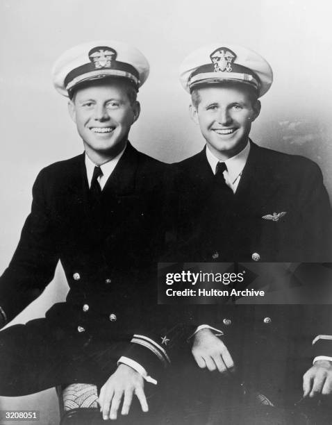 Portrait of young John F. Kennedy sitting next to his brother Joseph Kennedy Jr, whose plane was shot down in World War II, both wearing naval...