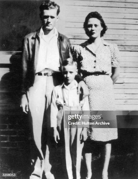 Elvis Presley standing between his parents outside of their home in Tupelo, Mississippi.