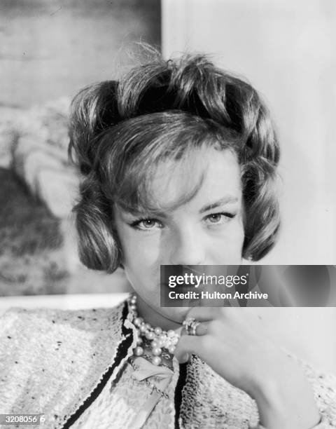 Headshot portrait of Austrian-born actor Romy Schneider holding her hand up to her chin. Her hair is styled in a bob.