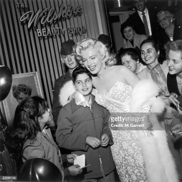 Marilyn Monroe smiles as she poses with fans in front of the Wilshire Beauty Shop at the premiere of director Jean Negulesco's film 'How to Marry a...