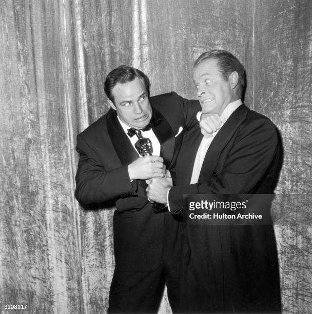 British-born entertainer Bob Hope jokingly tries to wrestle an Oscar statuette away from American actor Marlon Brando, backstage at the Academy...
