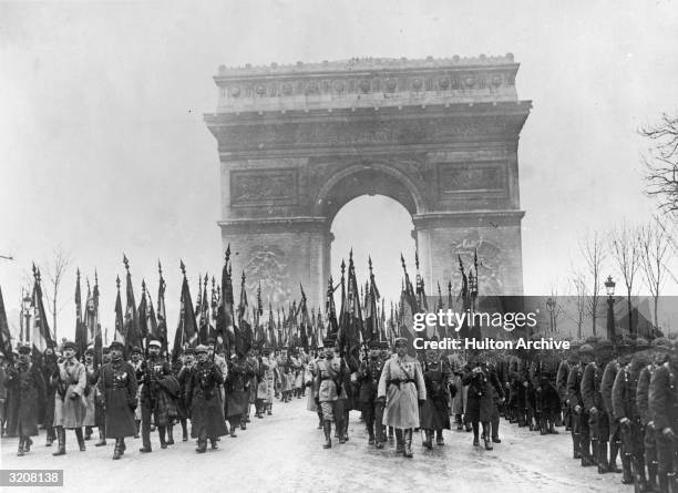 French veterans marching by the Tomb of the Unknown Soldier in Paris on the anniversary of Armistice Day. In the background the Arc de Triomphe is...