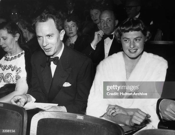 Swedish-born actor Ingrid Bergman smiles as she sits with her husband, Dr. Petter Lindstrom, in the audience for an awards ceremony, 1940s. She wears...