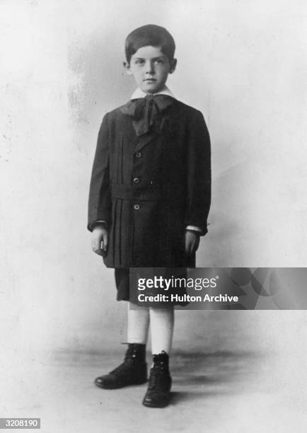 Full-length studio portrait of American actor and comedian Milton Berle as a young boy, 1910s. He wears a suit with breeches, a cravat, and lace-up...