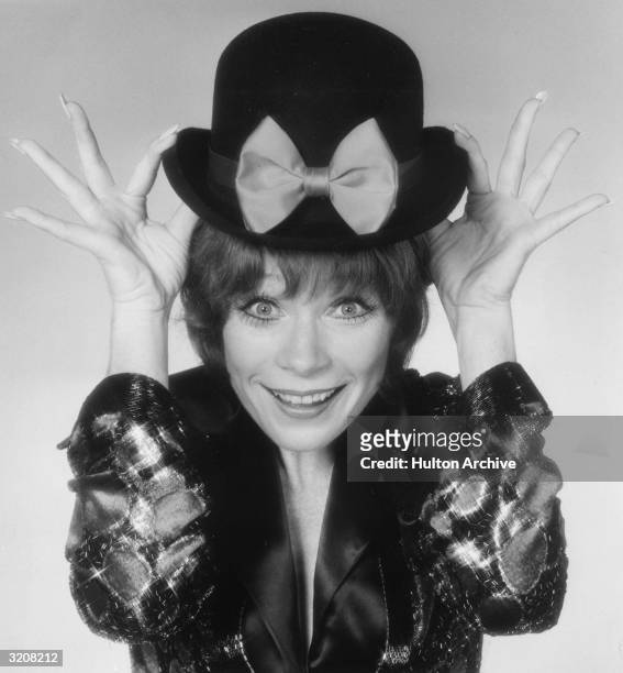 American actor and entertainer Shirley MacLaine smiles as she tips her bowler hat in a promotional portrait for her television special, 'If They...