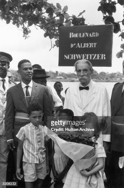 German-born missionary, humanitarian and physician Dr. Albert Schweitzer standing with men and children during a ceremony naming a street after him....