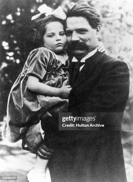 Portrait of German-born missionary, humanitarian, physician, and Nobel Peace prize winner Dr Albert Schweitzer holding his daughter, Rhena, outdoors.