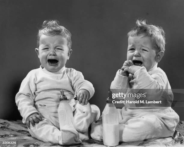 Crying twin babies with bottles.