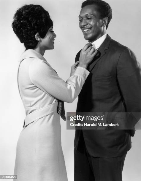 Studio portrait of a woman straightening a man's tie.