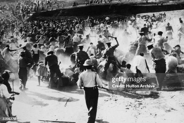 South African police beating Black women with clubs after they raided and set a beer hall on fire in protest against apartheid, Durban, South Africa.