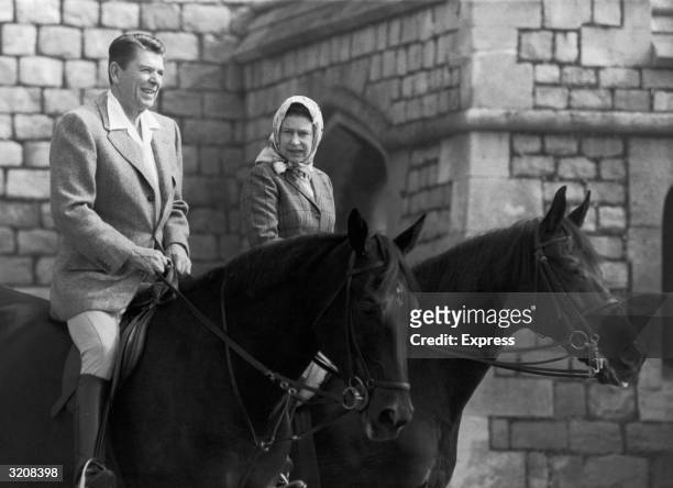 American President Ronald Reagan and Queen Elizabeth II engaged in conversation while horseback riding on the grounds of Windsor Castle, Windsor,...