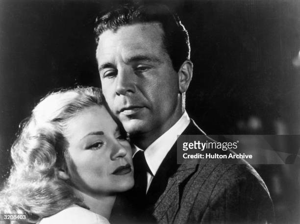 American actors Claire Trevor and Dick Powell embrace in a promotional portrait for director Edward Dmytryk's film, 'Murder, My Sweet'.