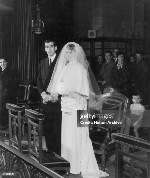 Full-length portrait of French actor Brigitte Bardot and her husband, French director Roger Vadim , standing at the altar during their wedding...