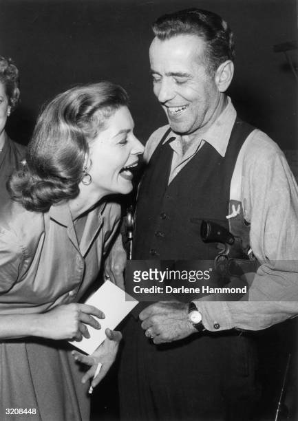 Married actors Lauren Bacall and Humphrey Bogart laughing on set between takes of the Producer's Showcase live telecast of 'The Petrified Forest', in...