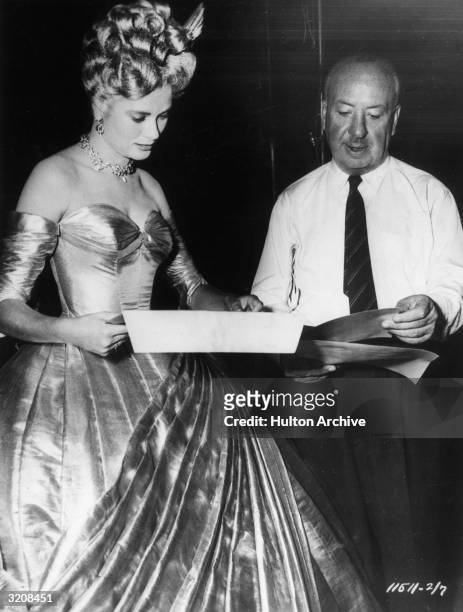 American actor Grace Kelly and British film director Alfred Hitchcock review a script on the set of the film, 'To Catch a Thief'. Kelly wears a...