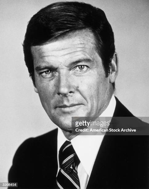 Studio headshot portrait of English actor Roger Moore wearing a jacket and tie.