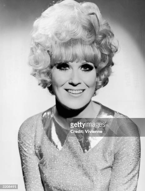 Headshot portrait of British singer Dusty Springfield , with dark eye-makeup, a large beehive hairdo, and a sparkling metallic dress. The portrait...
