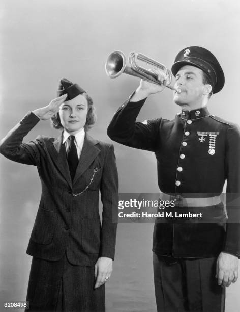Studio portrait of a woman in military uniform saluting next to a uniformed man playing the bugle.