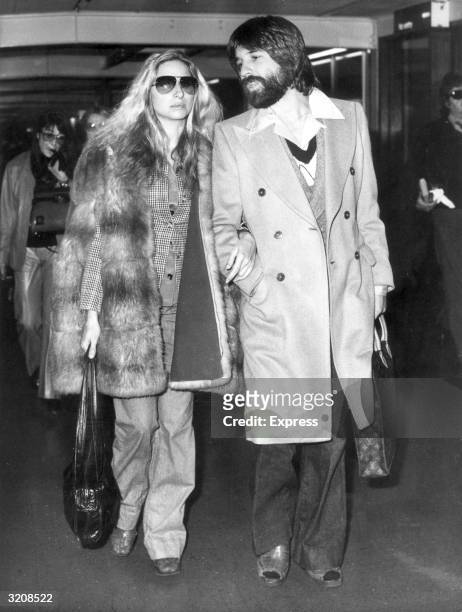 American actor Barbra Streisand walks with her boyfriend, Jon Peters, in London Airport before the Royal premiere of director Herbert Ross's film,...