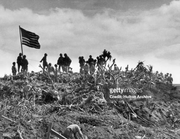 View of marines planting a US flag on Mount Suribachi, Iwo Jima, Japan, World War II. This was the second flag raised that day, being larger than the...