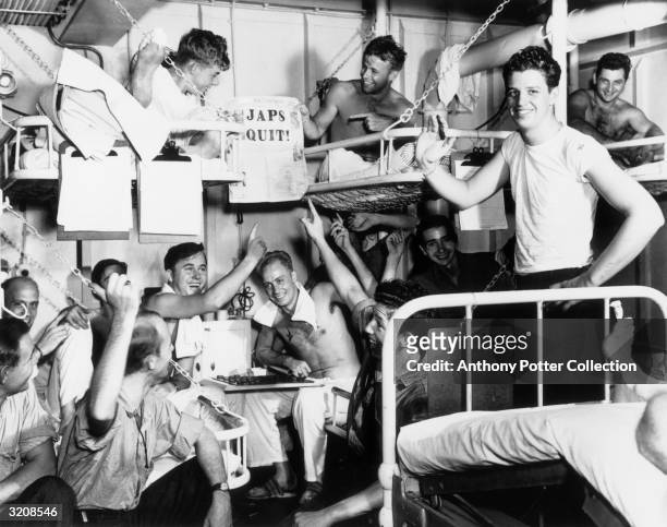 Servicemen in the sick bay of the S.S. Casablanca smile and point to a newspaper with the headline 'JAPS QUIT!', after the Japanese surrender in...