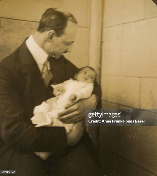 Otto Frank, father of Anne Frank, holds his infant daughter, Margot on the balcony of his home, Frankfurt am Main, Germany. Taken from the photo...