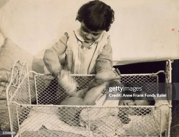 Anne Frank getting her buttocks powdered in a crib by her sister Margot Frank, Frankfurt am Main, Germany. From Anne Frank's photo album.