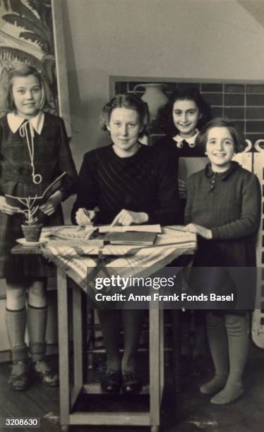 Group portrait of Martha Berg, teacher Miss Gordon, Anne Frank and Rela Solomon in a classroom at a Montessori school. Taken from Anne's photo album,...