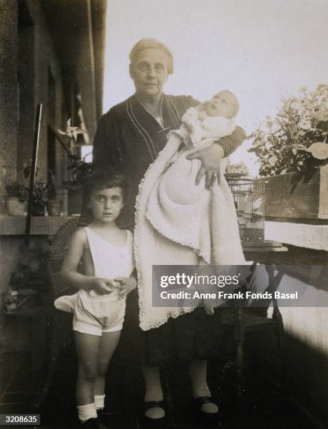 Anne Frank being held by her paternal grandmother Alice Frank-Stern next to her sister Margot Frank on a balcony, Frankfurt am Main, Germany. From...