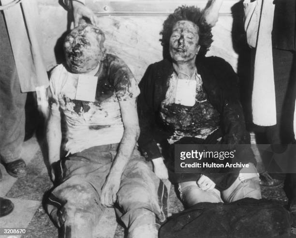 View of the mutilated bodies of Benito Mussolini and his mistress, Clara Petacci, propped up against a marble wall in Milan, Italy, World War II. The...