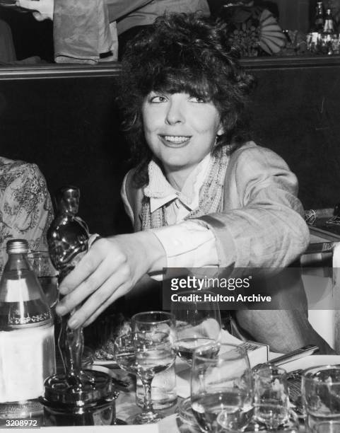American actor Diane Keaton places her Oscar statuette on a table in a restaurant following the Academy Awards, Los Angeles, California. She received...