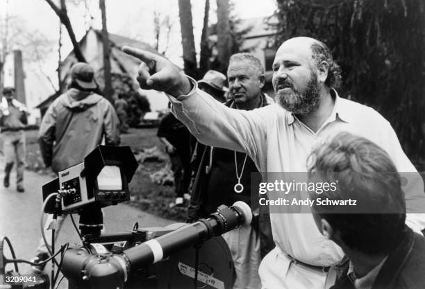 American director, producer, and actor Rob Reiner gestures near a camera while crew members surround him outdoors on the set of his film, 'North'