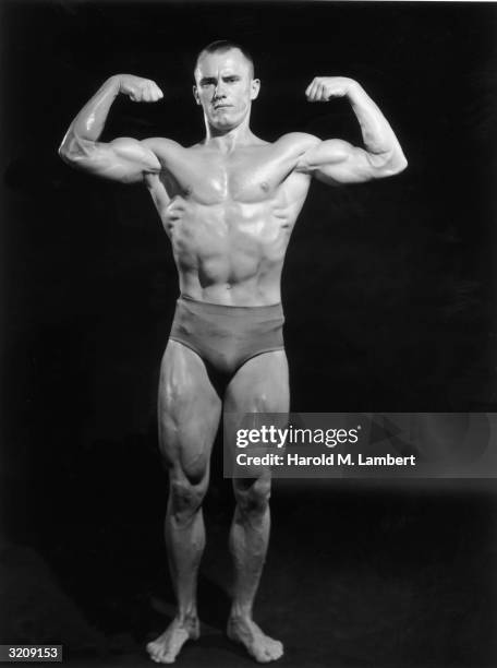 Full-length studio portrait of a male body builder flexing both arms.