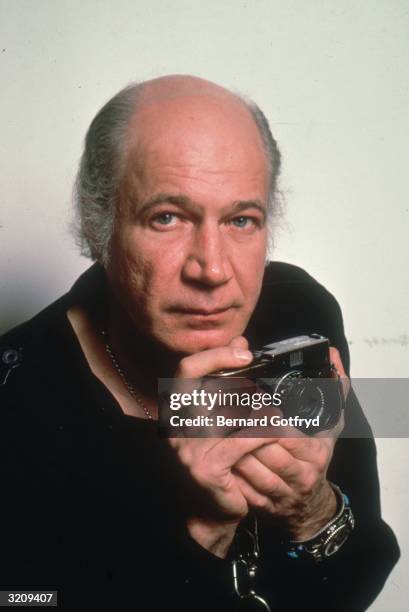 Headshot studio portrait of photographer Eddie Adams holding a camera. He worked for The Associated Press and won the 1969 Pulitzer Prize for his...