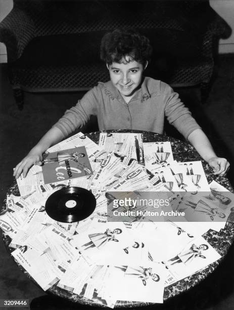 American pop and country singer Brenda Lee sits on the floor behind a coffee table covered with copies of her album, 'Brenda Lee,' and press...