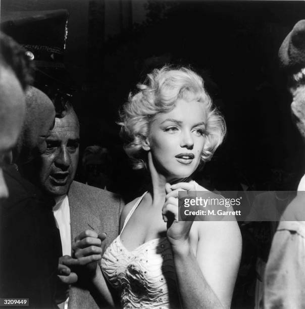 Portrait of actress Marilyn Monroe surrounded by reporters and fans outside Grauman's Chinese Theater in Hollywood, California