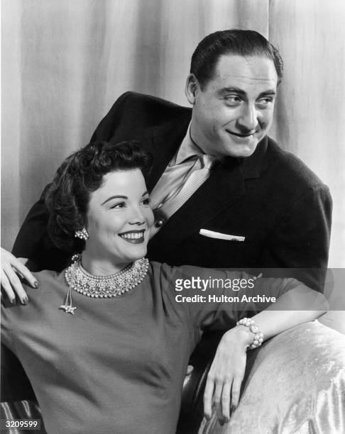 American actors Sid Caesar and Nanette Fabray smile while posing together on a sofa, possibly in a promotional portrait for the television series,...