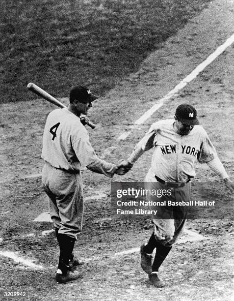 First baseman Lou Gehrig of the New York Yankees shakes hands with teammate Babe Ruth as he crosses the plate during a 1932 World Series game against...