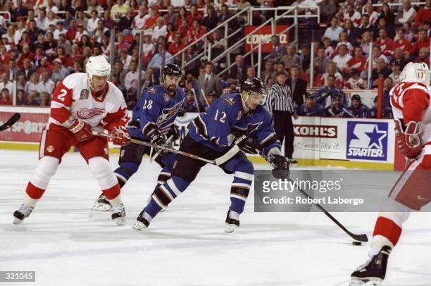 Peter Bondra of the Washington Capitals is hooked by Viacheslav Fetisov of the Detroit Red Wings during a Stanley Cup Finals game at the Joe Louis...