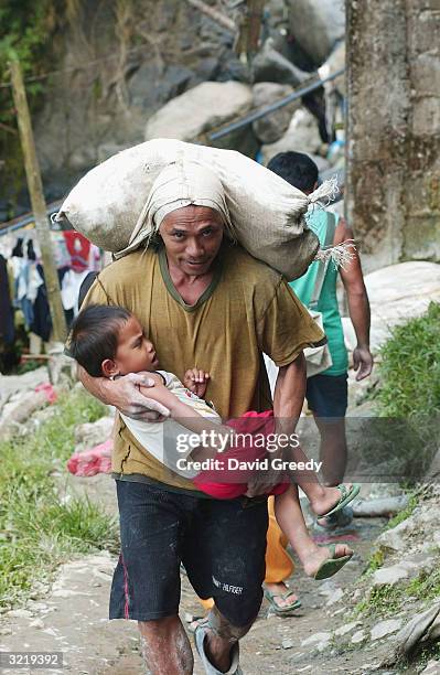 Gold mine worker carries a 40-50 kilogram bag of raw ore and his son on April 3, 2004 in the remote Mt. Diwata community on the southern island of...