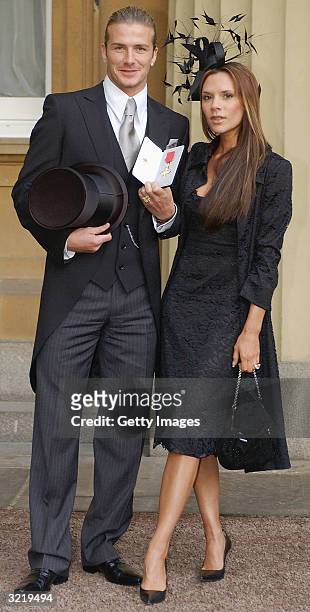 England football captain David Beckham stands with his wife Victoria, as he shows off the OBE he received from Britain's Queen Elizabeth II at...