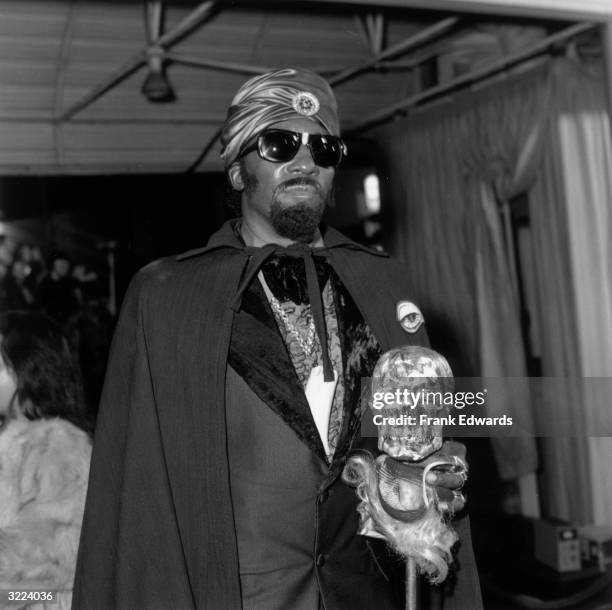 American R&B musician Screamin' Jay Hawkins attends the premiere of director Floyd Mutrux's film, 'American Hot Wax'. He wears a tuxedo, turban, cape...