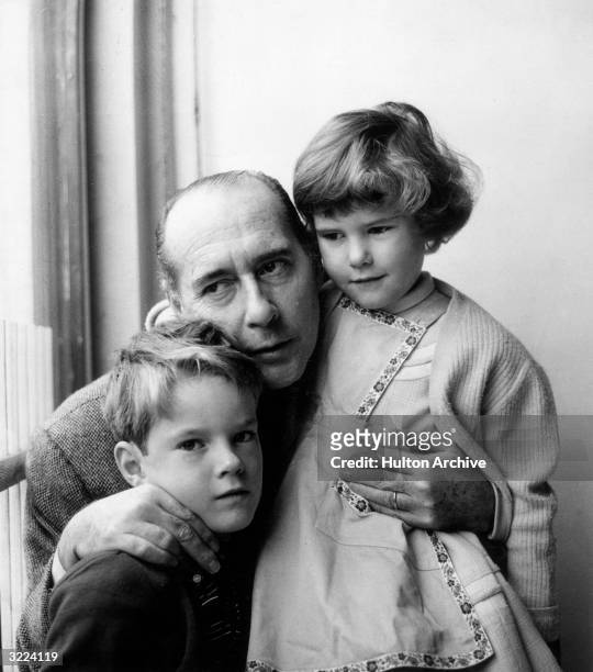 Italian film director Roberto Rossellini stands by a window, holding his son Roberto and his daughter Isotta, at their home in Rome, Italy.