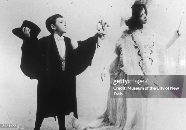 Full-length studio portrait of American actor and dancer Fred Astaire holding a bouquet of flowers towards his sister and dance partner, Adele...