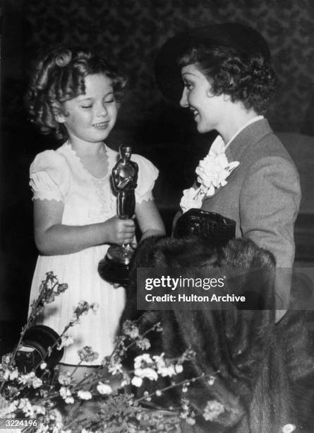 American actor Shirley Temple presents the Best Actress Oscar to French-born actor Claudette Colbert for her role in director Frank Capra's film, 'It...