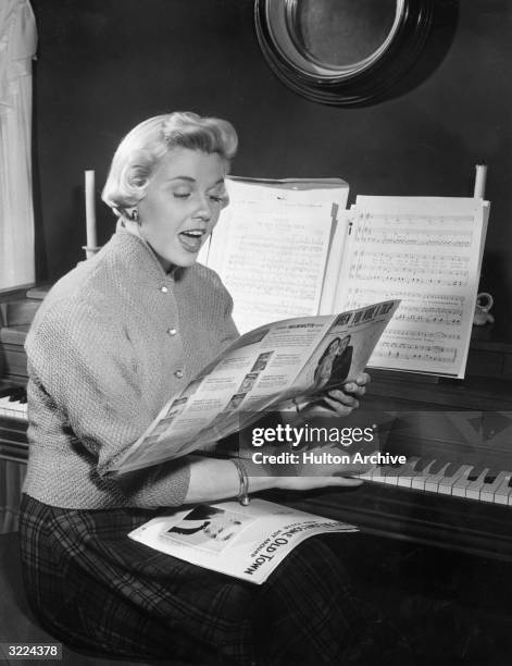 American actor and singer Doris Day sitting at a piano and singing while reading sheet music for 'When You Wore a Tulip ' from 'For Me and My Gal'.