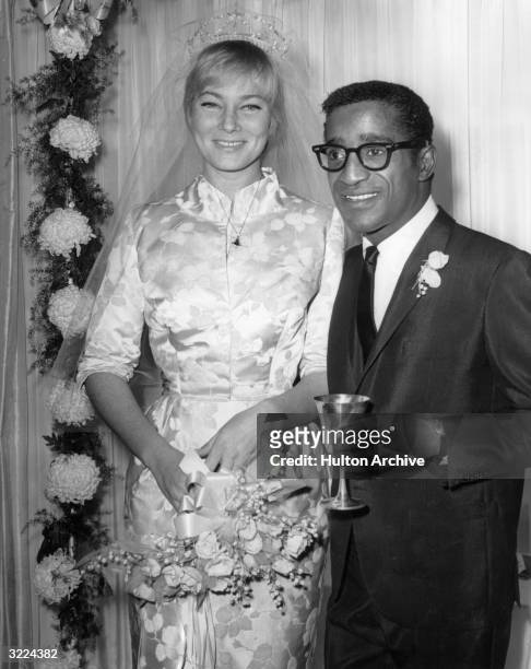 American actor, singer and dancer Sammy Davis Jr. Stands next to his wife, Swedish actor May Britt, at their wedding reception at Davis's home,...