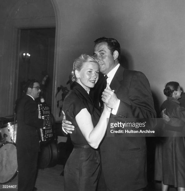 American actor and singer Doris Day dancing with her third husband, agent Marty Melcher, at a party. A musician plays the accordion in the background.