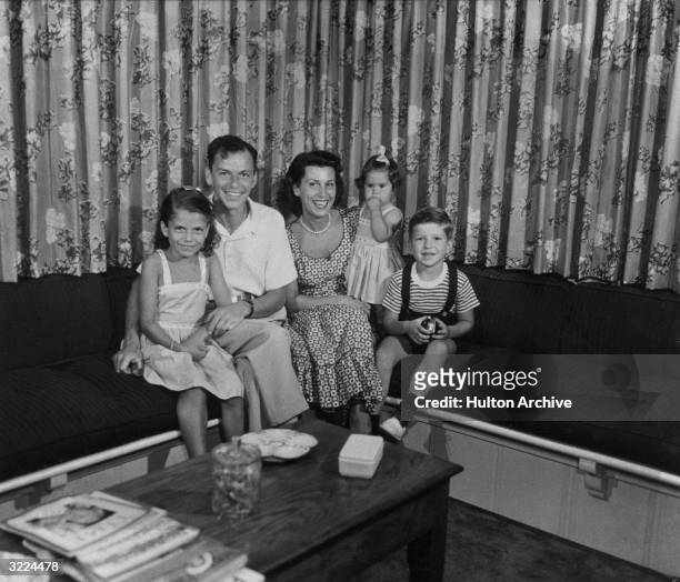Family portrait of American singer and actor Frank Sinatra sitting on a couch with his first wife, Nancy Barbato, and their children Nancy , Tina ,...
